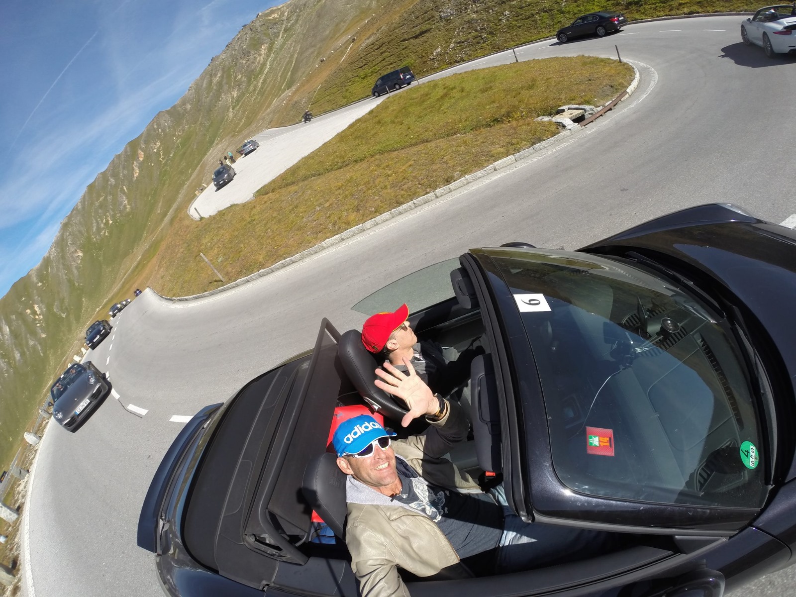 Selfie on alpine hairpin with convoy behind